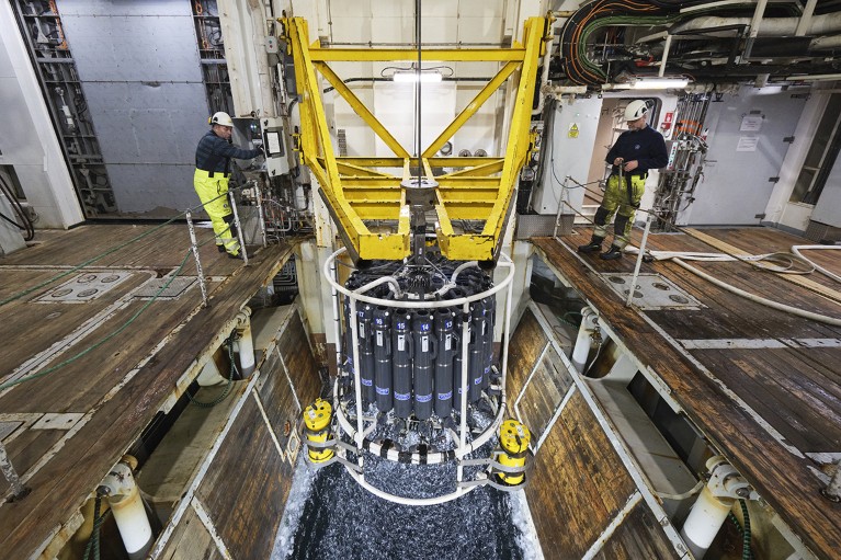 Two crew members recover multiple water samples in the Greenland Sea through the moon pool of RV Kronprins Haakon