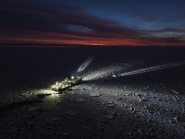 RV Kronprins Haakon in the dark has its lights reflecting off the pack ice of the Greenland Sea at dawn.