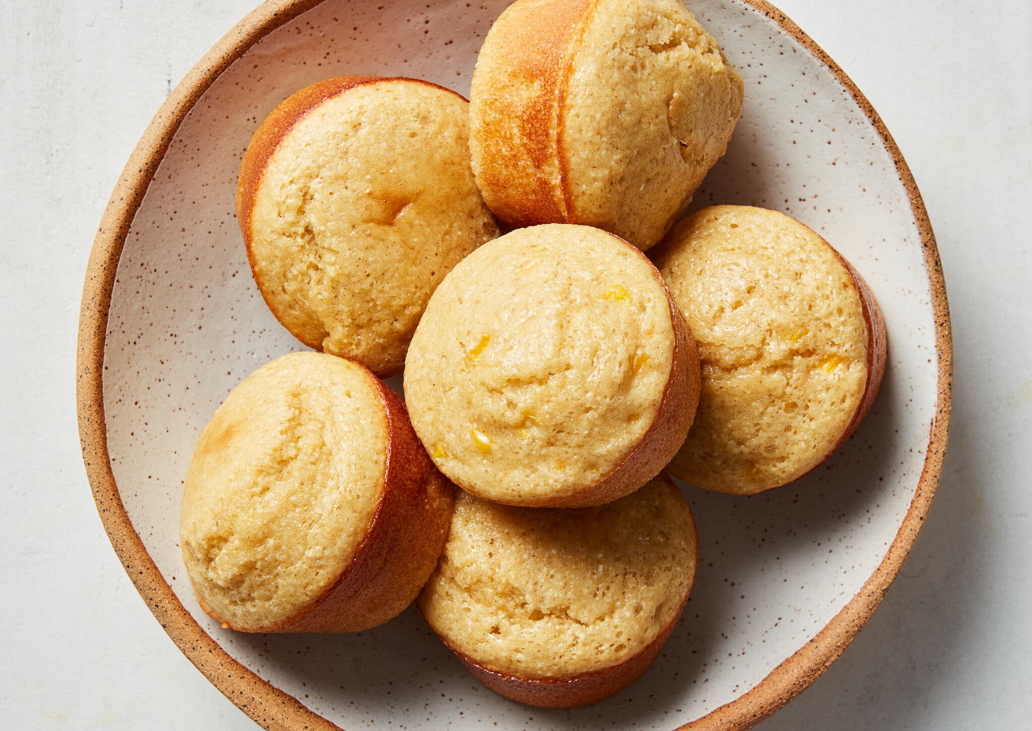 A ceramic bowl holds six cornbread muffins. 