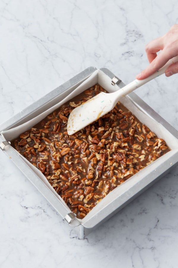 Spreading pecan filling evenly over the shortbread layer.