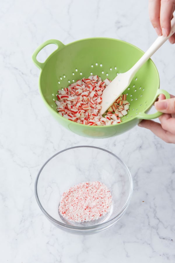 Sifting candy cane pieces in a berry bowl to remove the fine dust.
