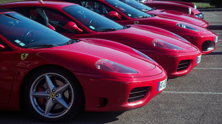 A line of Ferrari 360 Modenas, an F430, an F355, and possibly a Triumph Spitfire, all red
